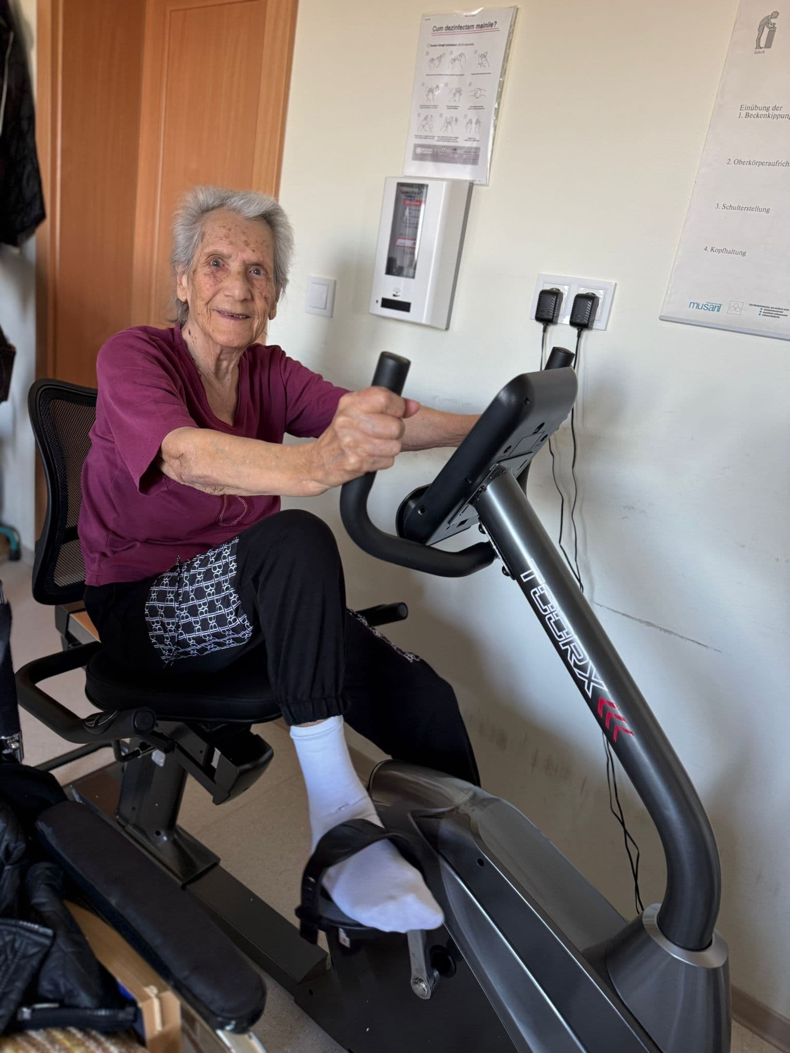 Rezidentă zâmbitoare pe bicicletă recumbentă la centrul Maria Theresia Sibiu